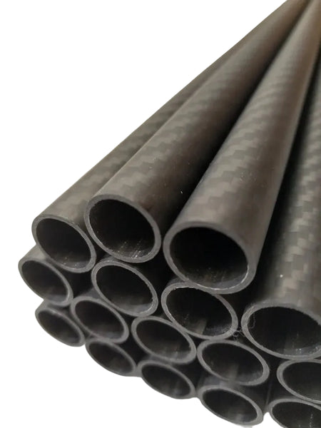 A stack of dark gray carbon fiber tubes with a visible carbon weave pattern, shown on a light background with text overlay reading '3K Carbon Fiber Tube 14mm x 12mm Matte Finish'.